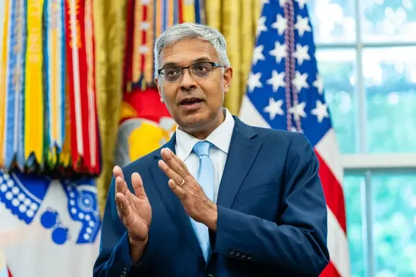 Jay Bhattacharya, directeur du NIH, gestiquant devant un drapeau américain et des rubans colorés.