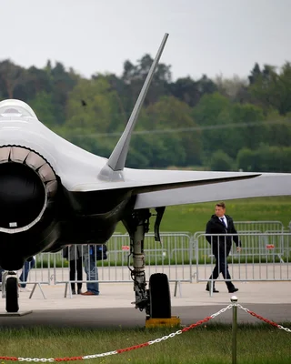 Vue rapprochée de la queue et du moteur d'un avion de chasse moderne garé au sol.