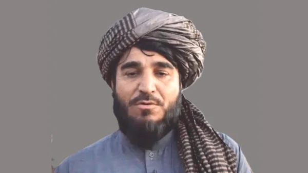Un responsable taliban portant un turban à carreaux et un vêtement bleu traditionnel.