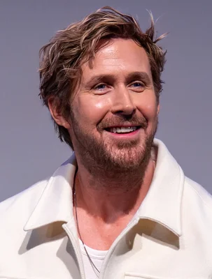 Ryan Gosling souriant en veste blanche lors d'un événement Barbie.