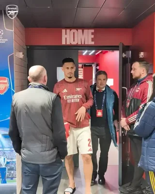 Un footballeur d'Arsenal traversant le tunnel des vestiaires accompagné de plusieurs personnes.