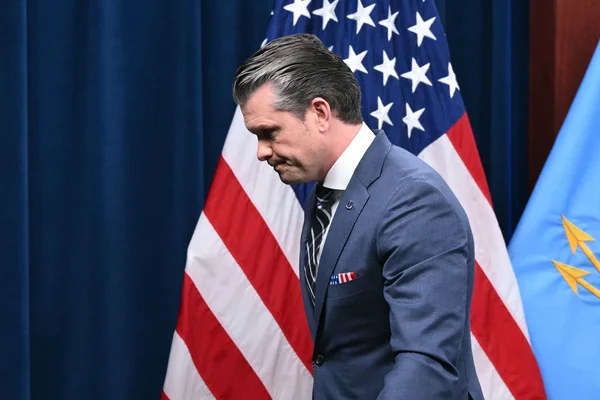 Portrait d'un homme en costume devant un drapeau américain.
