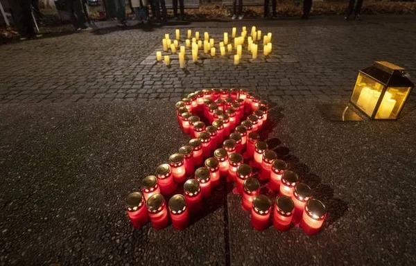 Hommage nocturne avec des bougies formant un ruban rouge, symbole de la lutte contre le VIH/SIDA.