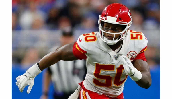 Un joueur de football américain en action lors d'un match, portant un maillot numéro 50.