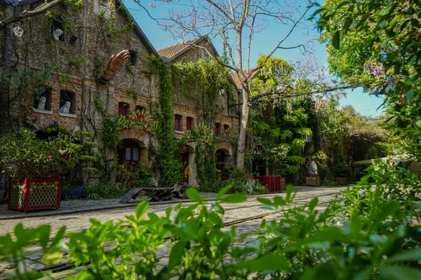 Visiteurs participant au Festival du Merveilleux 2023 aux Pavillons de Bercy, devant un bâtiment décoré de lumières et d'une sculpture de main.