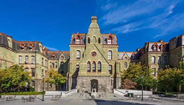 Un bâtiment historique aux façades de pierre verte et toits en tuiles rouges sur le campus de l'Université de Pennsylvanie.