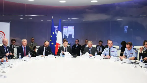 Réunion officielle autour d'une grande table blanche avec des drapeaux de l'Union européenne et de la France