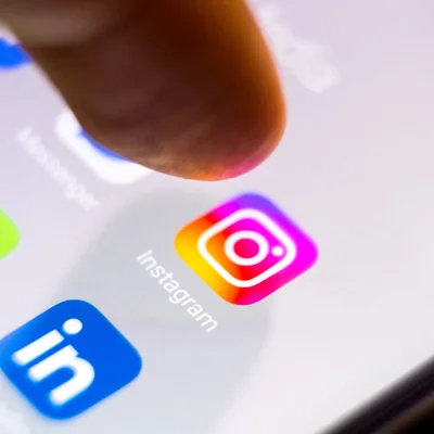 Un doigt prêt à appuyer sur l'icône Instagram, illustrant l'accès instantané aux réseaux sociaux.