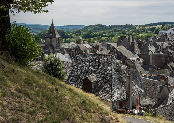 Un village typique de l'Aubrac avec son clocher érigé au milieu des collines verdoyantes.