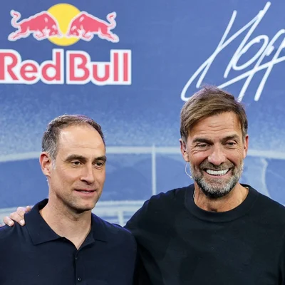 Deux hommes posant devant un fond aux couleurs de Red Bull.