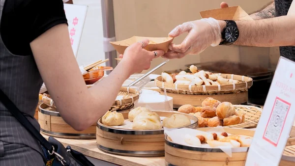 Un vendeur remet un contenant de nourriture à un client sur un étal de street food