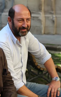 Kad Merad en 2014, assis sur un banc à l'extérieur.