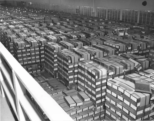 Photographie en noir et blanc d'un entrepôt rempli de boîtes de cartes perforées aux Archives nationales en 1959.