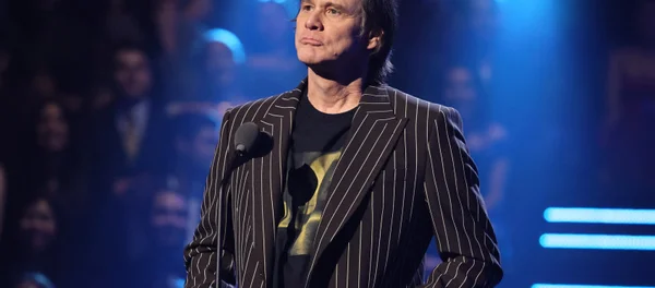 Jim Carrey sur scène devant un micro lors d'un discours.