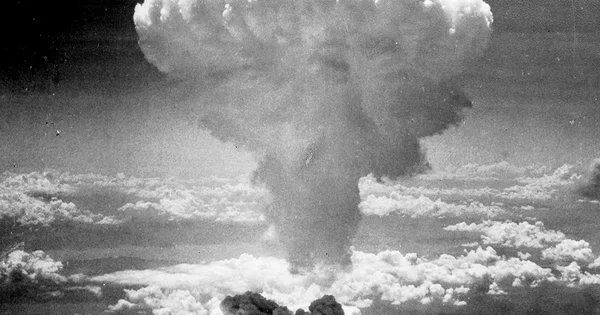 Photo en noir et blanc d'un énorme champignon nucléaire s'élevant dans les nuages, typique d'une explosion atomique.