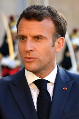 Emmanuel Macron en costume sombre, photographié lors d'un événement officiel en extérieur.