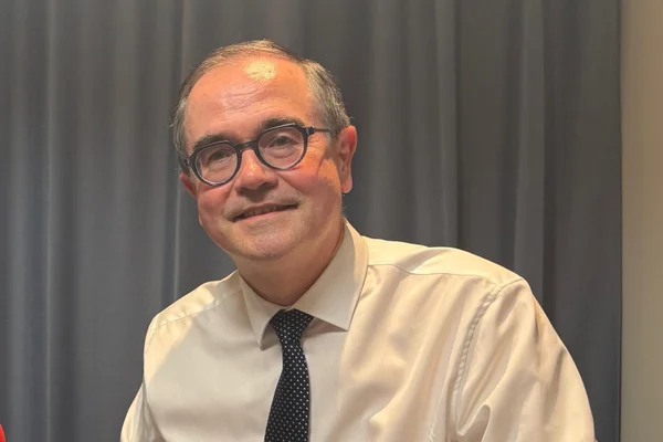 François Provost dans un cadre professionnel devant un rideau gris.