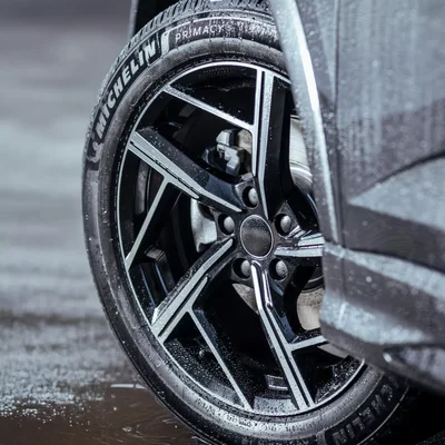 Pneu Michelin Primacy 5 sur jante argentée avec gouttes d'eau, illustrant une conditions humide.
