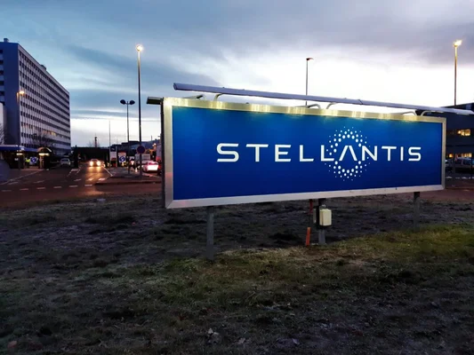L'enseigne lumineuse Stellantis visible au crépuscule dans une zone industrielle.