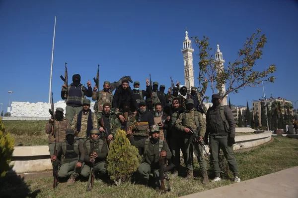Un groupe d'hommes armés posant à l'extérieur devant une mosquée.