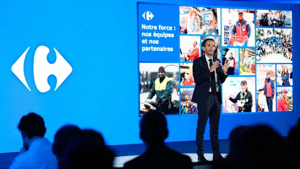 Alexandre Bompard devant un écran Carrefour avec ses équipes et partenaires