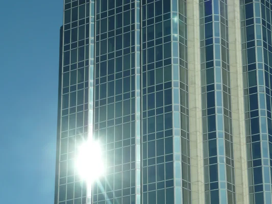 Le bâtiment d'Accenture à Vancouver avec une façade en verre réfléchissante sous un ciel bleu.