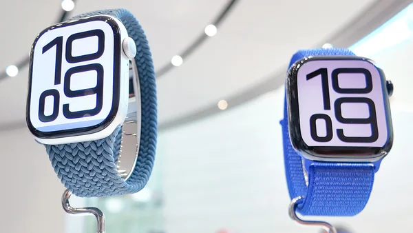 Deux montres connectées avec bracelets bleus exposées sur des supports dans un espace de vente lumineux.