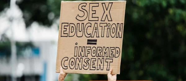 Une personne tenant une pancarte revendiquant l'éducation sexuelle comme un consentement éclairé.