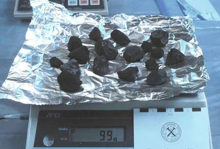 Des fragments de la météorite Tagish Lake pesés sur du papier aluminium dans un laboratoire.