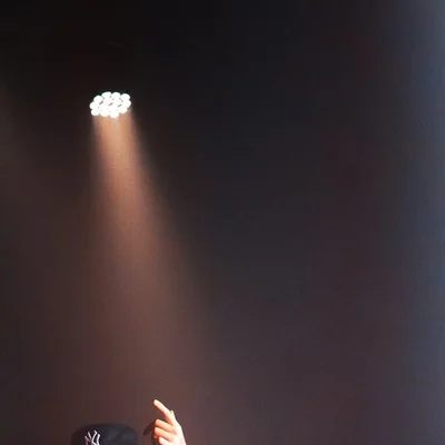 Une main du public pointée vers la scène illuminée pendant un concert.