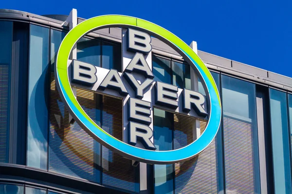 L'enseigne Bayer en relief sur la façade vitrée d'un bâtiment sous un ciel dégagé.