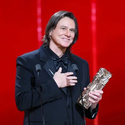 Jim Carrey tenant une récompense et posant la main sur la poitrine.