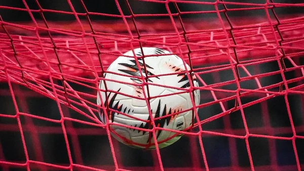 Une rangée de ballons de football posés sur l'herbe d'un stade