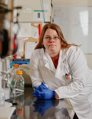 Chercheuse en laboratoire en blouse blanche travaillant sur du matériel scientifique.
