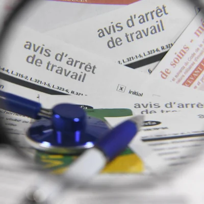 Un stéthoscope bleu posé sur des documents d'avis d'arrêt de travail.