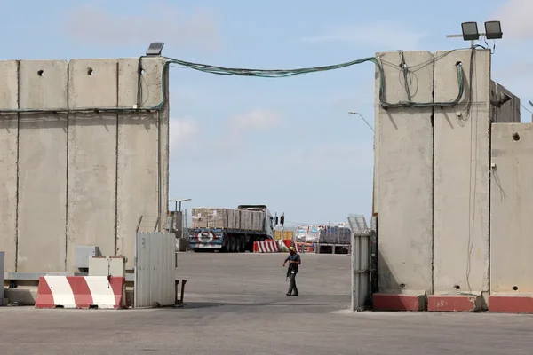 Vue du point de passage de Kerem Shalom avec un piéton et des camions.