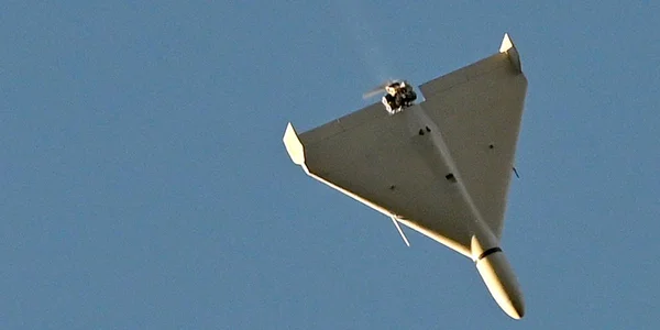 Un véhicule aérien sans pilote de forme triangulaire survolant une zone sous un ciel dégagé.