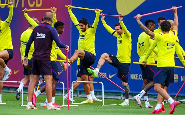 Joueurs du Barça lors d'un exercice d'étirement collectif à l'entraînement, encadrés par un coach.