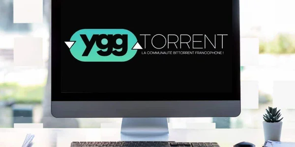 Un écran d'ordinateur affichant le logo YggTorrent posé sur un bureau de travail
