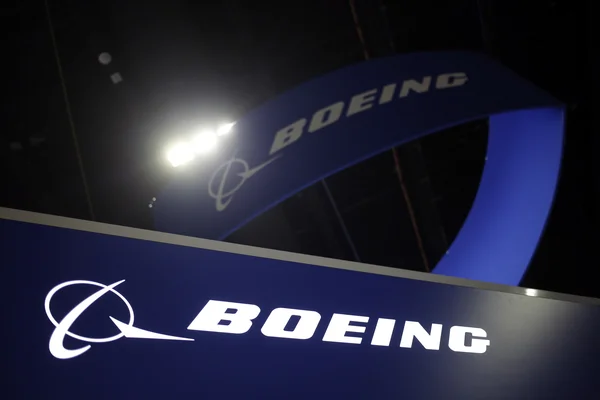 Panneau bleu avec le logo et le nom de l'entreprise Boeing sous un éclairage artificiel.