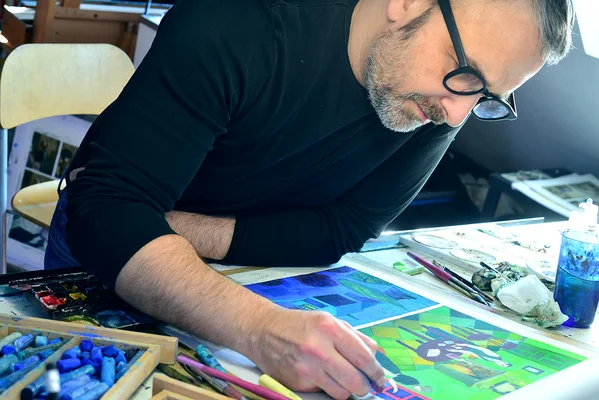 David Sala au travail dans son atelier entouré de crayons et de peintures.