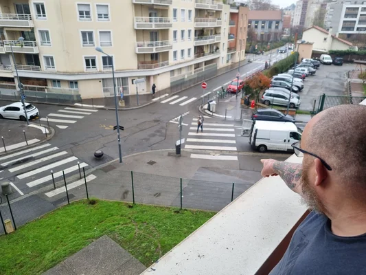 Un riverain montrant du doigt le lieu de tirs depuis son balcon à Villeurbanne, dénonçant l'insécurité.