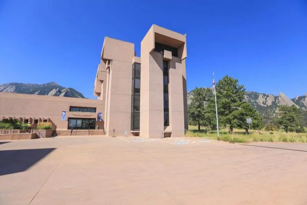 Bâtiment de recherche du NCAR avec sa tour caractéristique, situé devant un panorama de montagnes.
