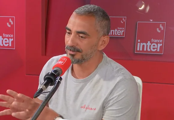 Julien Mairesse interviewé sur France Inter, micro rouge en main, devant un fond rouge aux logos de la station radio.