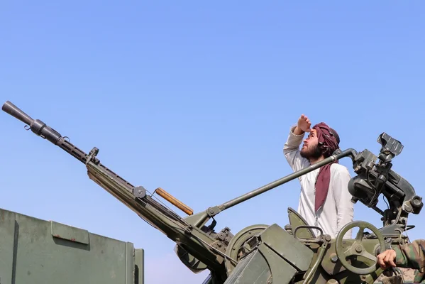 Un combattant près d'une mitrailleuse montée sur un véhicule militaire.