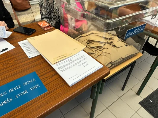 Une urne et des documents sur une table de bureau de vote.