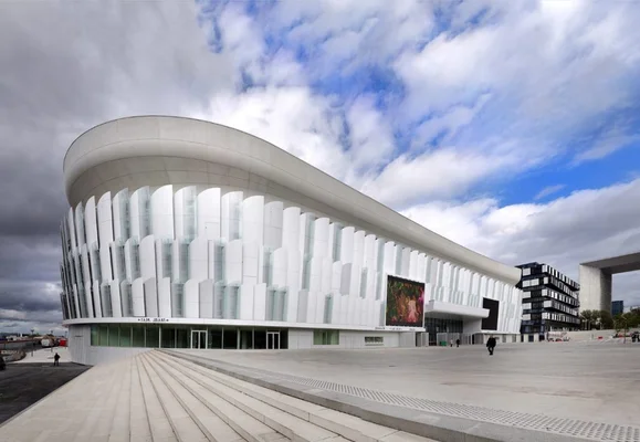 Façade de la Paris la Défense Arena avec son grand écran numérique et la place pavée au premier plan.