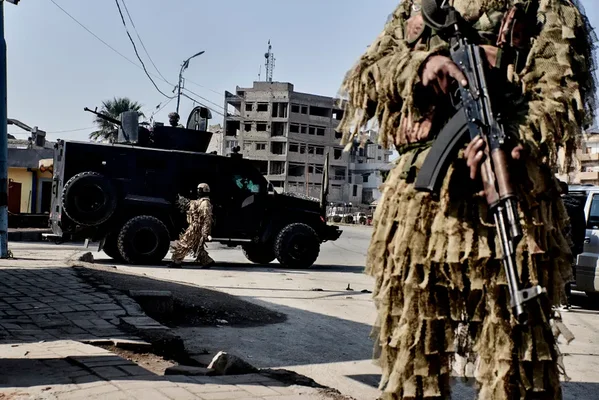 Un soldat en tenue de camouflage ghillie tenant un fusil d'assaut.