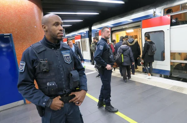 Des agents de sûreté de la RATP surveillent le quai d'une station de métro parisienne.