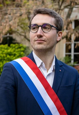 Antoine Léaument portant l'écharpe tricolore de député lors d'une cérémonie officielle.